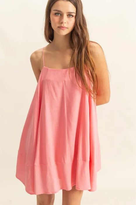 Front view of a woman wearing a pink loose-fit swing mini dress with spaghetti straps, perfect for a casual summer look.