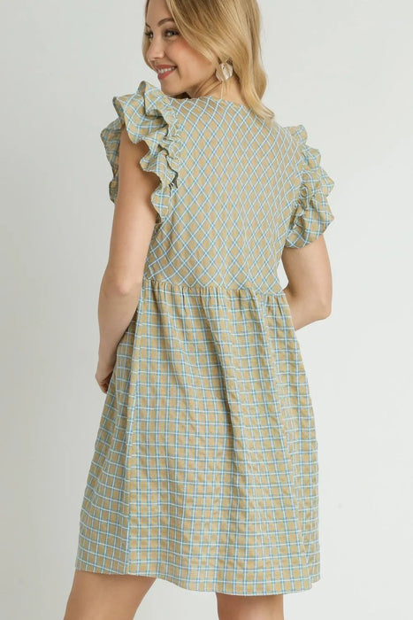 Back view of a woman wearing a tan and blue plaid babydoll dress with ruffled sleeves and a gathered waistline