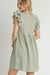 Back view of a woman wearing a tan and blue plaid babydoll dress with ruffled sleeves and a gathered waistline