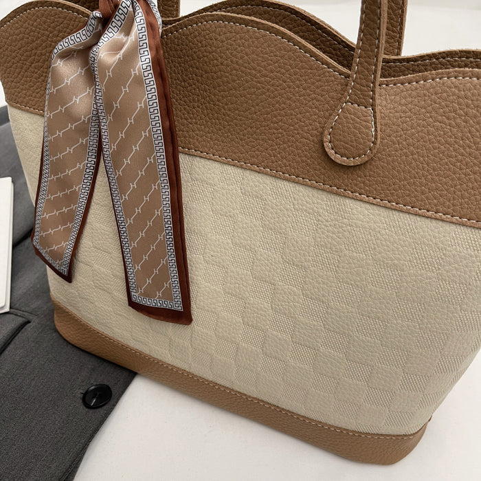 Close-up view of a tan checkered tote bag with brown faux leather trim and a silk scarf tied on the handle