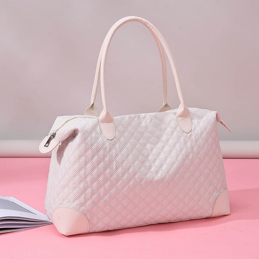 Elegant pink quilted handbag with soft top handles, displayed on a pink surface with a zipper closure design.