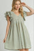 Woman wearing a tan and blue plaid dress with ruffled cap sleeves, a V-neckline, and front button detail, styled in a casual and playful look
