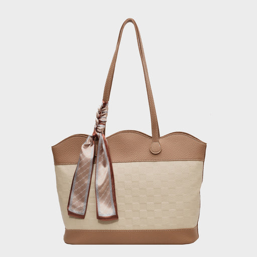 Elegant tan leather tote bag with checkered beige canvas body, finished with a decorative silk scarf tied to the handle.
